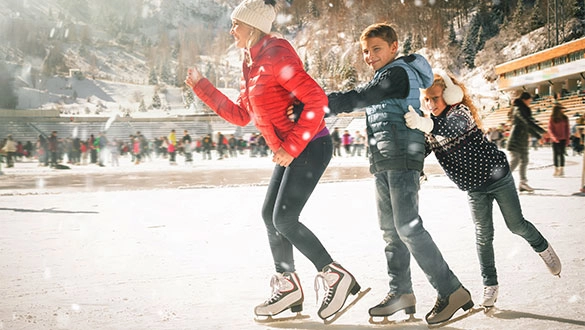 Familie beim Schlittschulaufen im Winter auf der Eisbahn