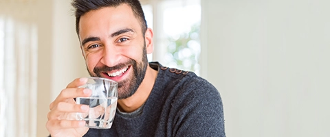 Lächelnder Mann mit Wasserglas, erfrischend und gesund. Perfekt für Wohlfühlmomente.