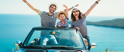 Fröhliche Familie genießt Cabriofahrt am Meer. Perfekter Sommerurlaub.