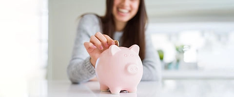 Frau spart Geld in Sparschwein, finanzielle Sicherheit, lächelnd.