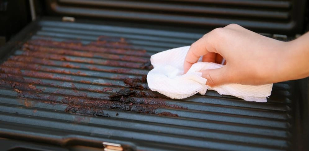 Frau reinigt Elektrogrill