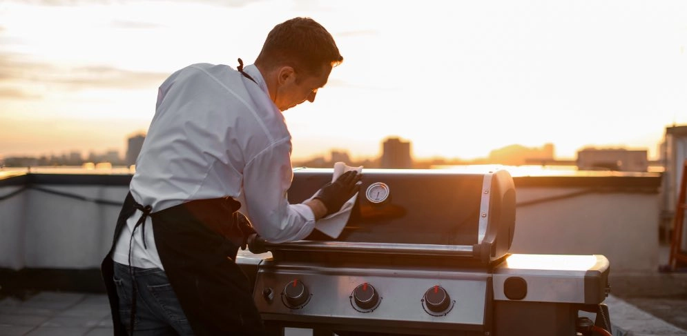 Mann reinigt Grillrost eines Gasgrills