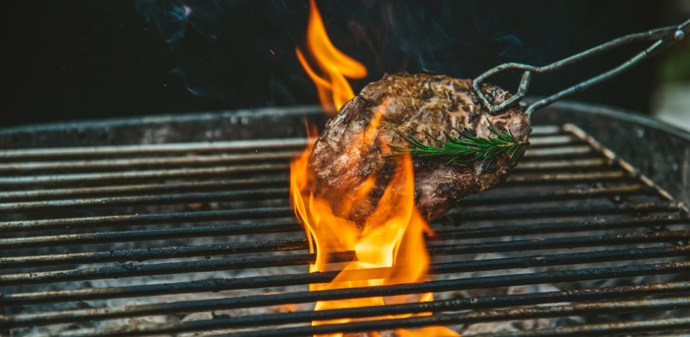 Saftiges Steak auf dem Grill mit Flammen, perfektes BBQ-Erlebnis.