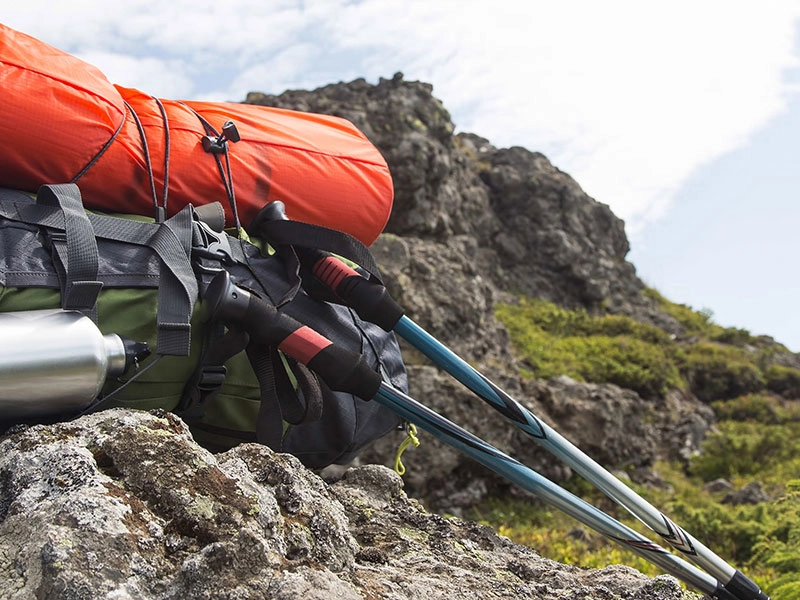 Trekking-Rucksack mit Wanderstöcken auf Felsen