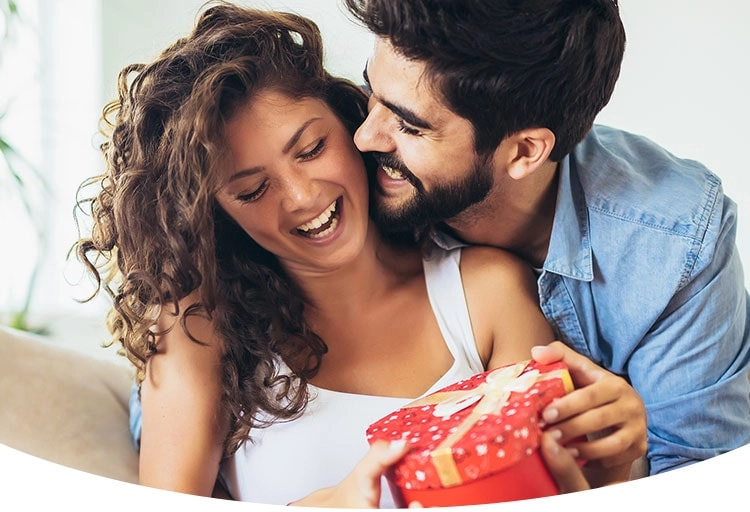 Ein Mann umarmt seine Frau und überreicht ihr ein Geschenk zum Hochzeitstag 