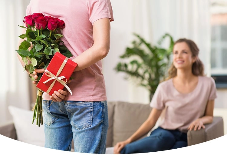 Ein Mann versteckt hinter seinem Rücken ein Jahrestag-Geschenk 