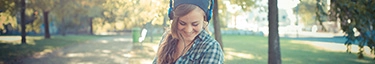 Frau genießt Musik im Park, entspannt und glücklich, ideal für Freizeit und Erholung.