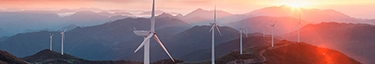 Windkraftanlagen bei Sonnenuntergang in malerischer Berglandschaft für nachhaltige Energie.