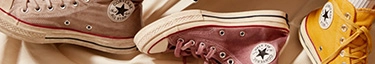Stylische Converse-Sneaker in Beige, Rot und Gelb auf beigem Hintergrund.