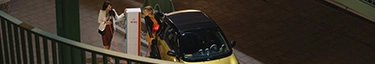 Elektroauto lädt an moderner E-Ladestation in urbaner Umgebung bei Nacht.