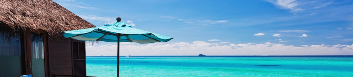 Traumhafte Strandkulisse mit türkisblauem Meer und Sonnenschirm, ideal für Erholung.