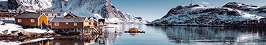 Norwegische Fjordlandschaft mit malerischen Hütten und schneebedeckten Bergen.