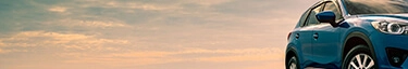 Eleganter blauer SUV vor dramatischem Himmel, ideal für Abenteuerreisen.