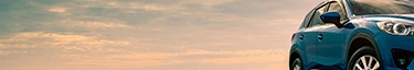 Elegantes blaues SUV vor dramatischem Himmel, ideal für Abenteuer und Stil.