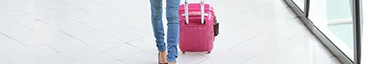 Reisende mit pinkem Koffer im modernen Flughafen, stilvoll und bereit für das nächste Abenteuer.