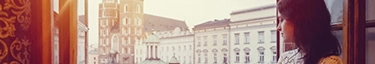 Frau genießt Kaffee mit Blick auf historische Stadtansicht bei Sonnenuntergang.