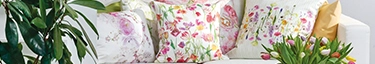 Blumige Kissen auf weißem Sofa, frühlingshafte Wohninspiration.
