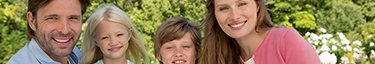 Fröhliche Familie im Garten, strahlende Gesichter, Natur, Harmonie, Lebensfreude.