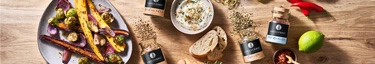 Gourmet-Gewürze und frische Zutaten auf Holztisch für kulinarische Inspiration.