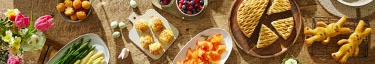 Frühlingsbrunch: Frische Speisen und Blumen auf rustikalem Holztisch.