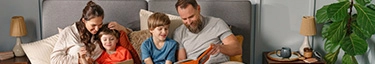 Gemütliche Familienzeit im Bett mit Büchern und Snacks, harmonische Atmosphäre.