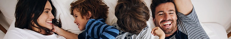 Glückliche Familie beim Kuscheln im Bett, vereint in Freude und Geborgenheit.