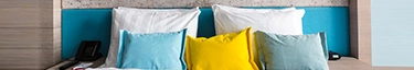 Modernes Hotelzimmer mit stilvollem Doppelbett und farbenfrohen Kissen für erholsamen Schlaf.
