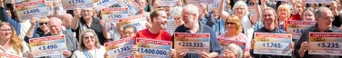 Gewinner der Postcode-Lotterie feiern mit strahlenden Gesichtern und Gewinnschecks.